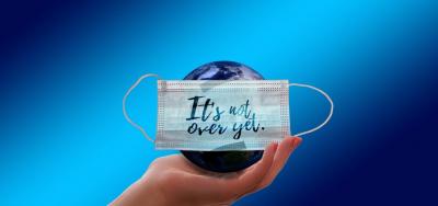 Graphic - Globe covered with mask and words "It's Not Over Yet".